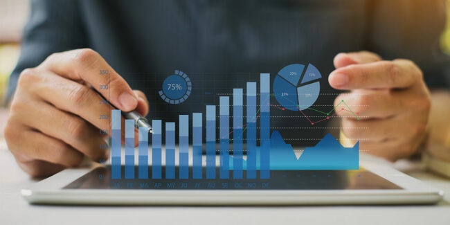 Hands using a tablet with overlaid bar, line, and pie charts for data analysis.